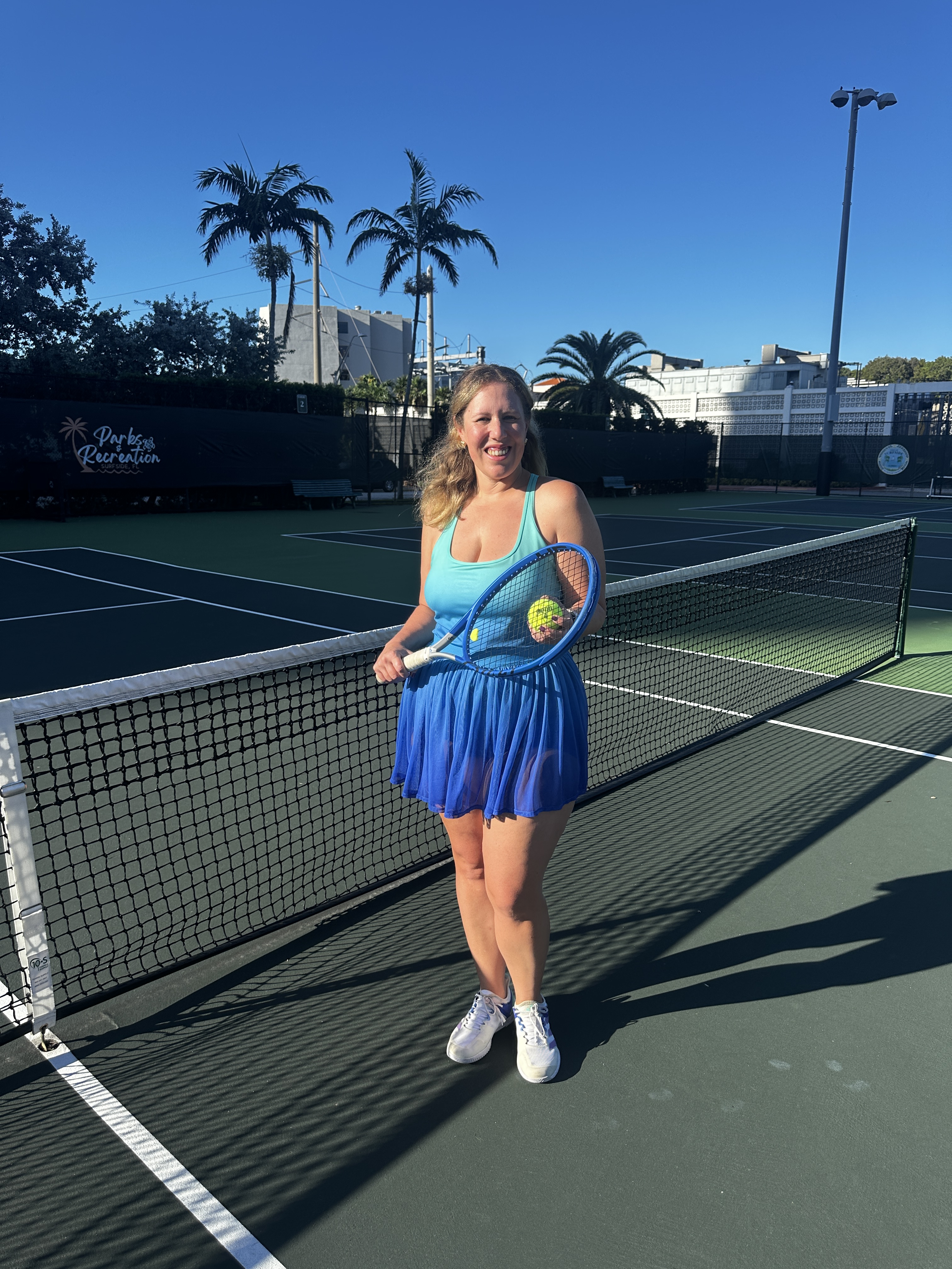 Lia Picard standing at a tennis net holding a racquet and ball