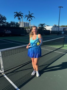 Lia Picard standing at a tennis net holding a racquet and ball